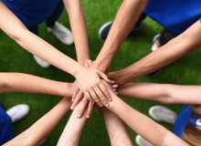 Group of volunteers joining hands together outdoors, top view